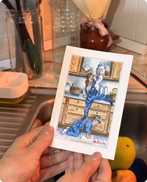Hand-drawn postcard of blue cartoon cats busy in a vintage kitchen, held in hands