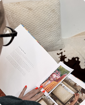 Open book on a couch with printed postcards tucked between the pages