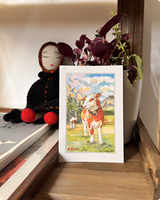 Standing card of a brown-and-white calf in an alpine meadow propped on a shelf