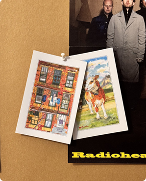 Brownstone facade and meadow cow postcards pinned to a cork board