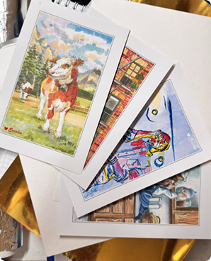 A fanned-out stack of hand-painted postcards spread on a desk
