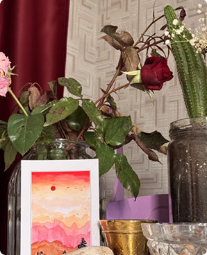 Pink layered mountain sunset postcard among rose stems and a cactus